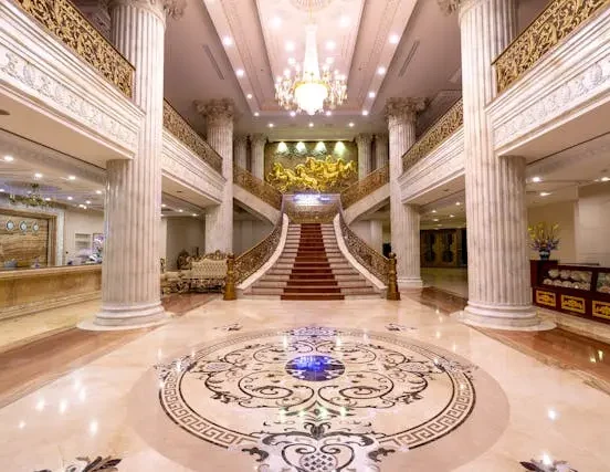 Luxury hotel lobby interior with grand staircase, marble columns, chandelier lighting, and elegant floor design